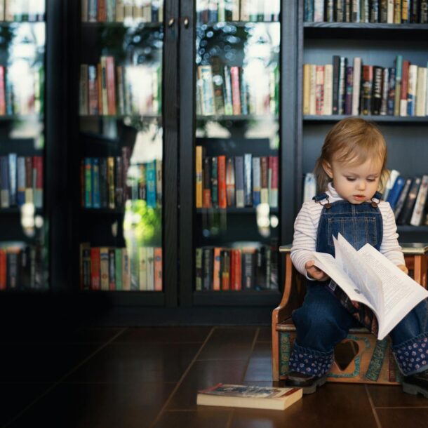 Toddler sitting on a Wooden Chair holding a Book