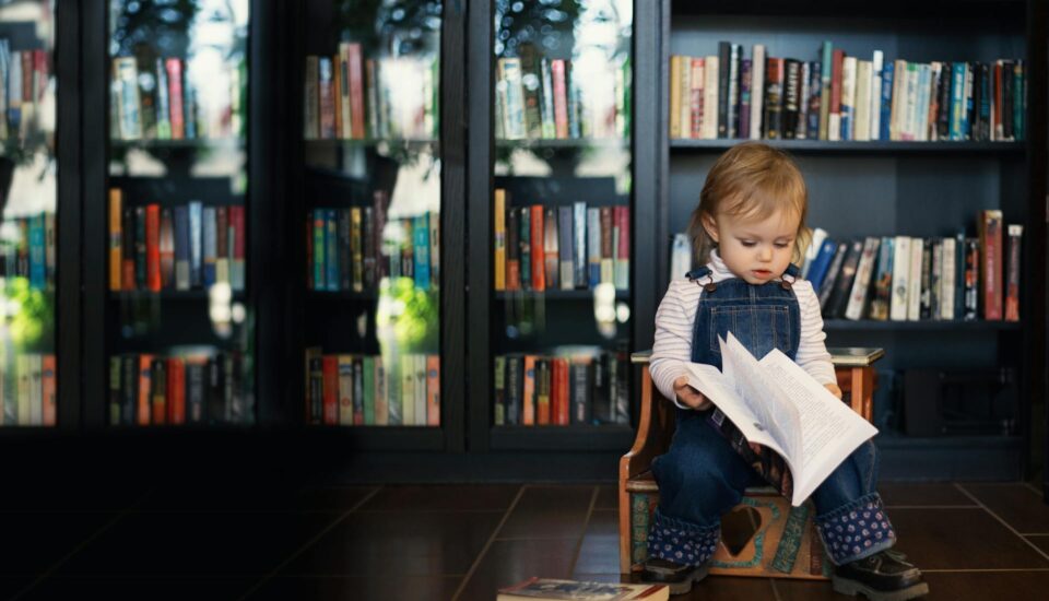 Toddler sitting on a Wooden Chair holding a Book